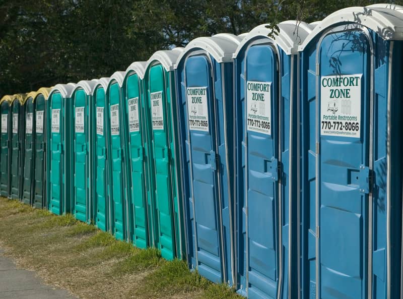 Restroom Trailer Rental in Minnesota: a line of portable restroom units set out in a row at a large staging area