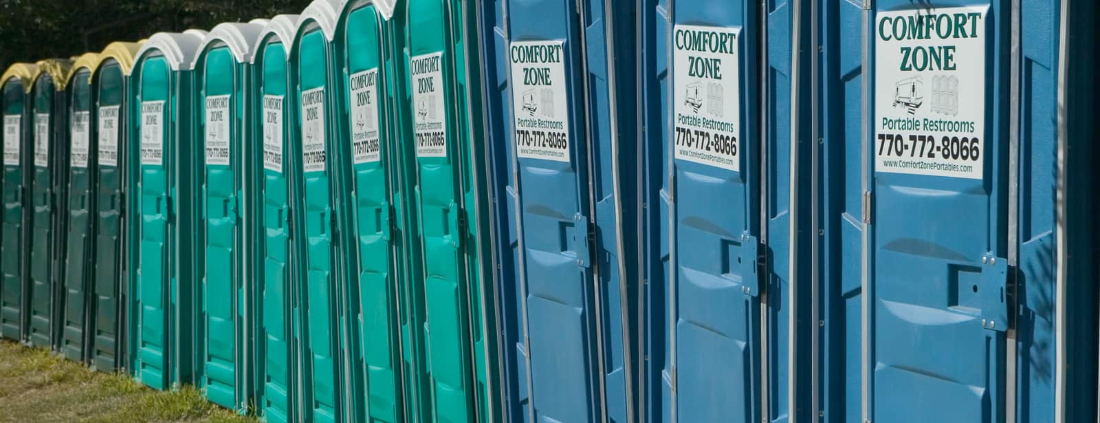 A line of portable restroom units set out in a row at a large staging area