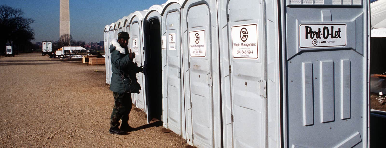 A long row of portable restroom units staged along a closed street for a large public event