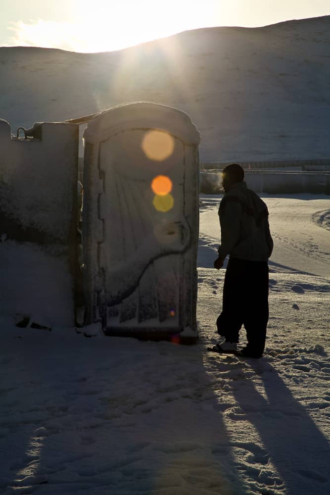 Porta Potty Rental in a Minnesota Winter: a portable restroom in use on a snow-covered site during a winter storm